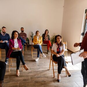 Businessman standing by a whiteboard and holding a presentation for a group of his coworkers