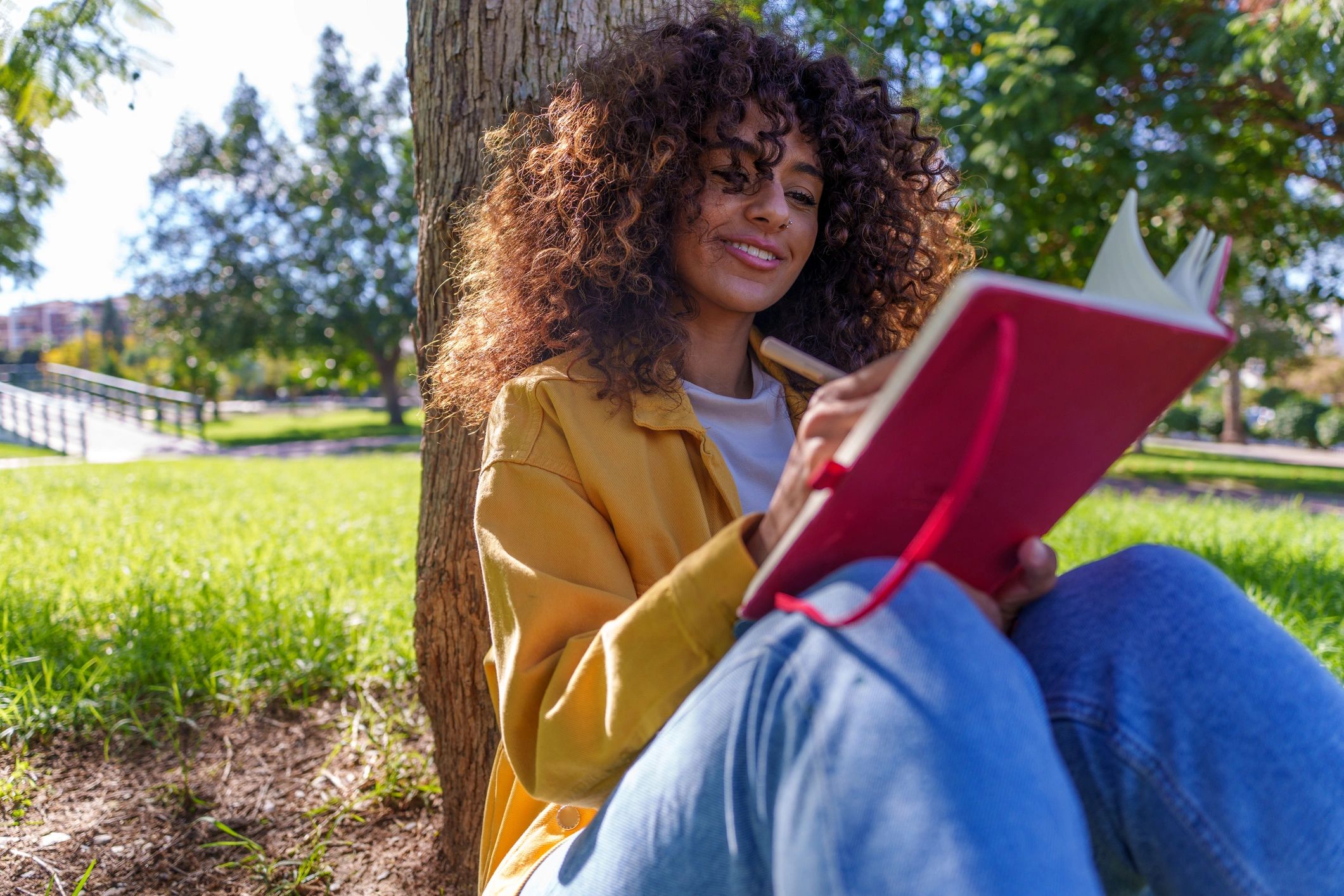 Woman writing in notebook outdoors in a peaceful natural setting